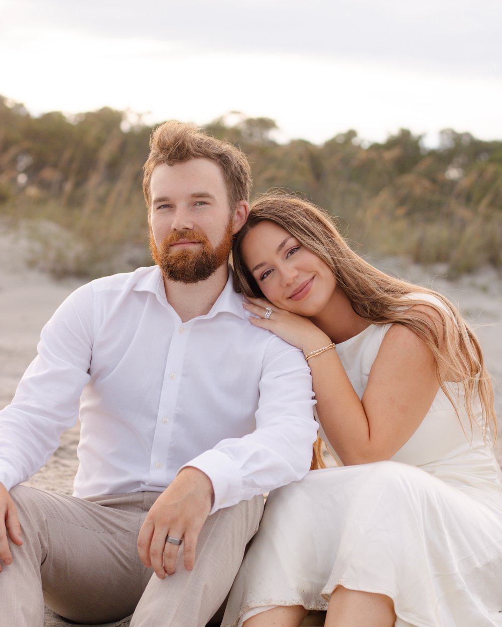 Smiling couple sitting close together on the beach