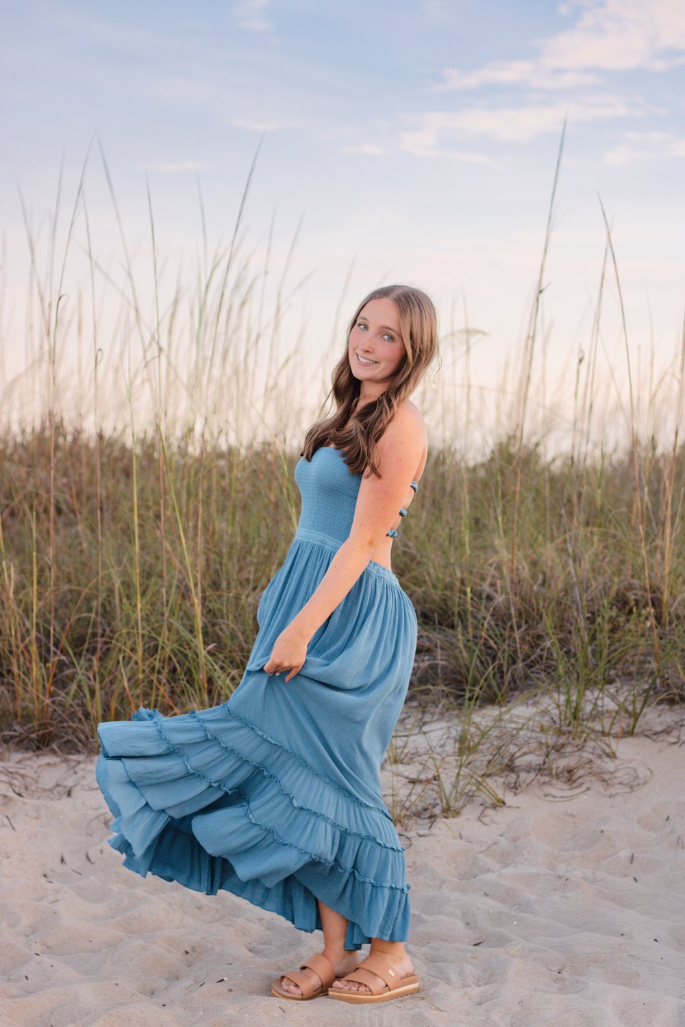 Graduate twirling her blue dress in the dunes at golden hour