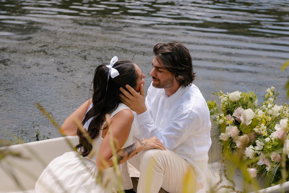 Overhead view of a couple embracing in a rowboat filled with white flowers